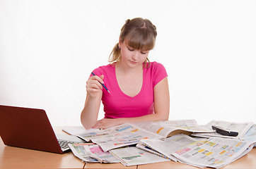 Image showing Girl looking for the right ad in newspaper