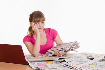 Image showing Sad girl with a stack of newspapers