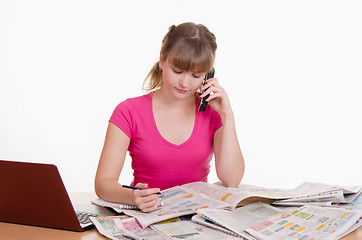 Image showing Young woman calling on a newspaper ad