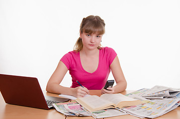 Image showing The girl writes a phone number from directory to notebook