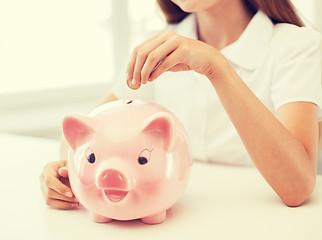 Image showing smiling child putting coin into big piggy bank