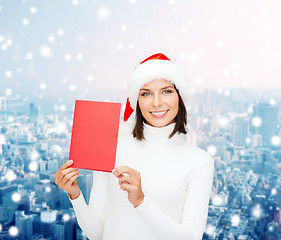 Image showing smiling woman in santa hat with greeting card