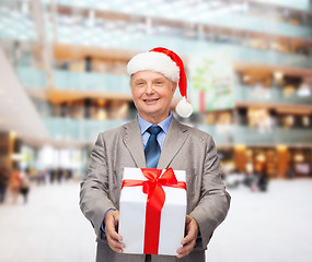 Image showing smiling man in suit and santa helper hat with gift