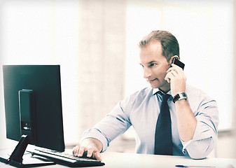 Image showing smiling businessman with smartphone in office