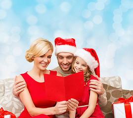Image showing happy family in santa hats with greeting card