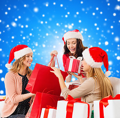 Image showing smiling young women in santa hats with gifts