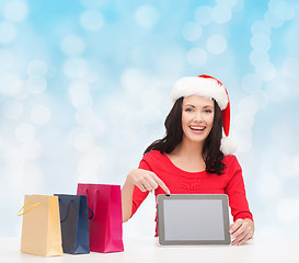 Image showing smiling woman in santa hat with bags and tablet pc