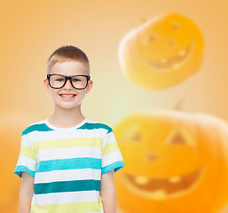 Image showing smiling boy in glasses over pumpkins background