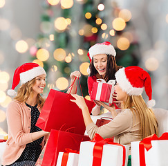 Image showing smiling young women in santa hats with gifts