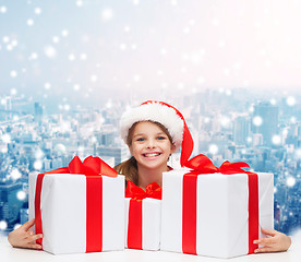 Image showing smiling girl in santa helper hat with gift boxes