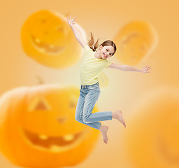 Image showing smiling girl jumping over pumpkins background