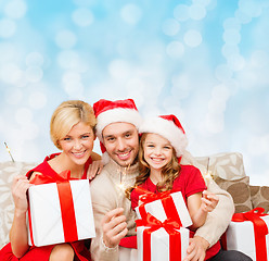 Image showing happy family in santa helper hats with gift boxes