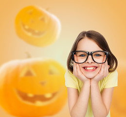 Image showing smiling girl in glasses over pumpkins background