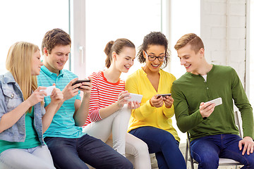 Image showing smiling students with smartphone texting at school