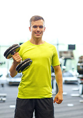 Image showing smiling man with dumbbell in gym