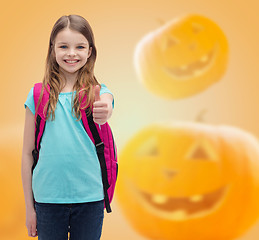 Image showing smiling girl in glasses over pumpkins background