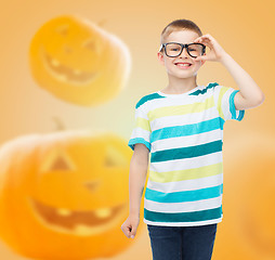Image showing smiling boy in glasses over pumpkins background