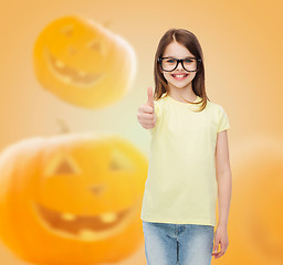 Image showing smiling girl in glasses over pumpkins background