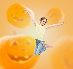 Image showing smiling girl jumping over pumpkins background