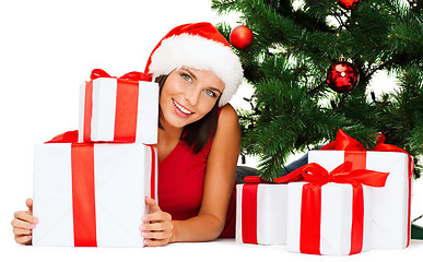 Image showing smiling woman in santa helper hat with gift boxes