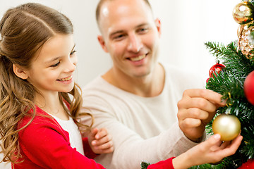 Image showing smiling family decorating christmas tree at home