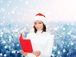 Image showing smiling woman in santa hat with greeting card