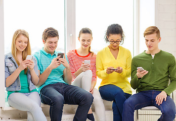 Image showing smiling students with smartphone texting at school