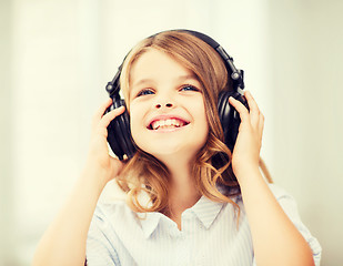 Image showing smiling little girl with headphones at home