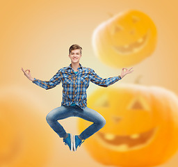 Image showing smiling young man jumping in air