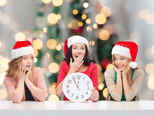 Image showing smiling women in santa helper hats with clock