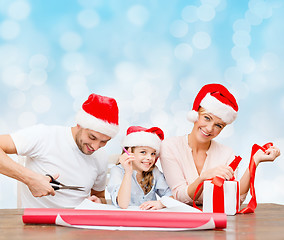 Image showing happy family in santa helper hats packing gift