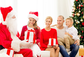 Image showing smiling family with santa claus and gifts at home