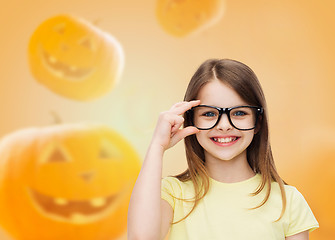 Image showing smiling girl in glasses over pumpkins background
