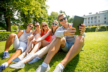 Image showing smiling friends with tablet pc computer in park