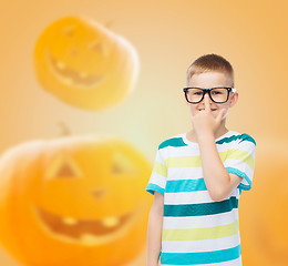 Image showing smiling boy in glasses over pumpkins background