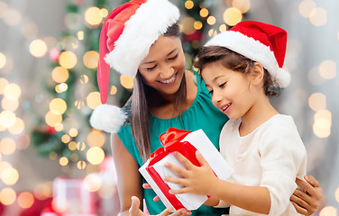 Image showing happy mother and girl in santa hats with gift box
