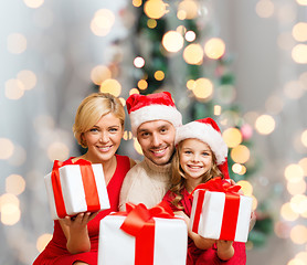 Image showing happy family in santa helper hats with gift boxes