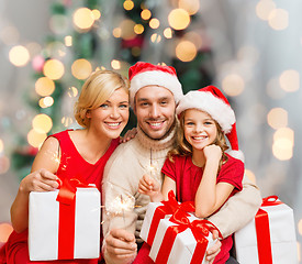 Image showing happy family in santa helper hats with gift boxes