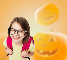 Image showing smiling girl in glasses over pumpkins background