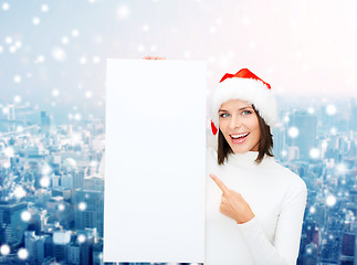 Image showing smiling young woman in santa hat with white board