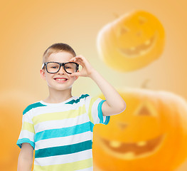 Image showing smiling boy in glasses over pumpkins background