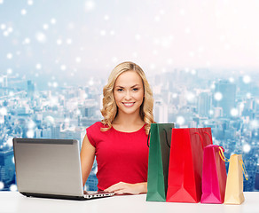 Image showing smiling woman in red shirt with gifts and laptop