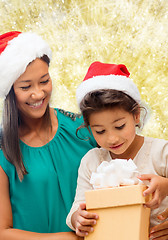 Image showing happy mother and girl in santa hats with gift box