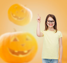 Image showing smiling girl in glasses over pumpkins background