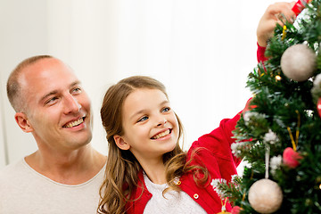 Image showing smiling family decorating christmas tree at home