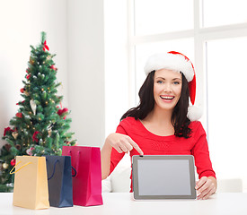 Image showing smiling woman in santa hat with bags and tablet pc