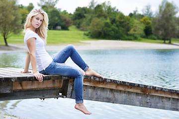 Image showing Blond woman sitting on a jetty