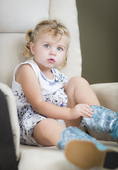 Image showing Blonde Haired Blue Eyed Little Girl Putting on Cowboy Boots
