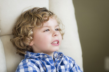 Image showing Cute Blonde Boy Daydreaming and Sitting in Chair