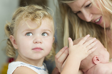 Image showing Young Mother Holds Newborn Baby Girl as Young Sister Looks